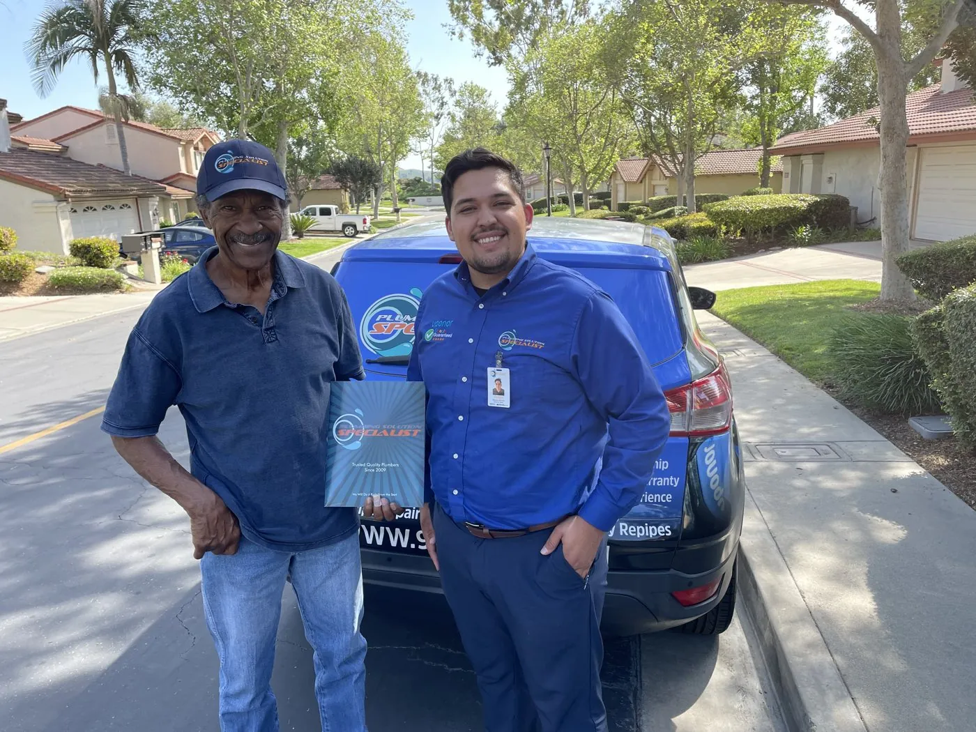 Two men beside a Plumbing Solution Specialist vehicle