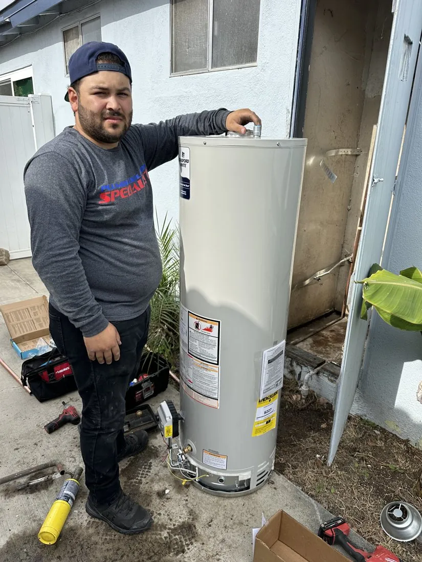 Plumbing technician beside a tank water heater